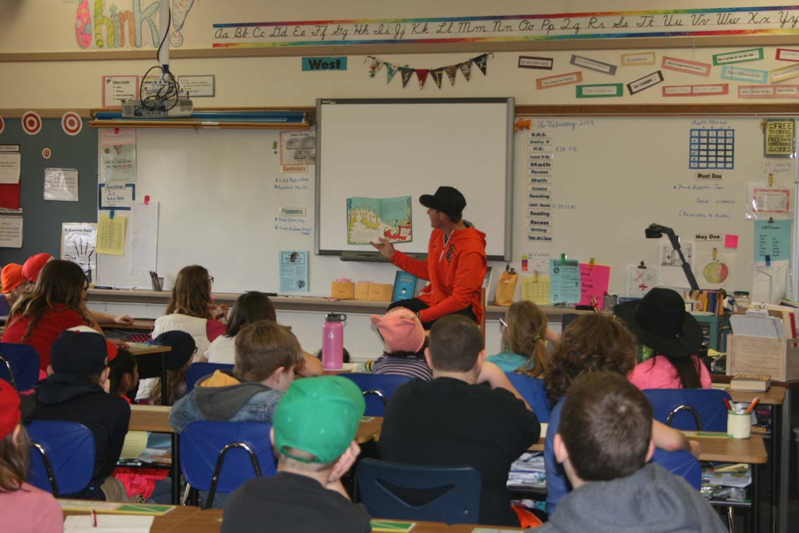 OSU student athlete reading a Dr. Seuss book to elementary students.